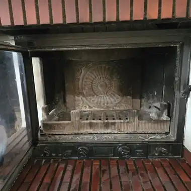 Foyer d’un insert de cheminée encrassé par la suie, porte ouverte, avant ramonage